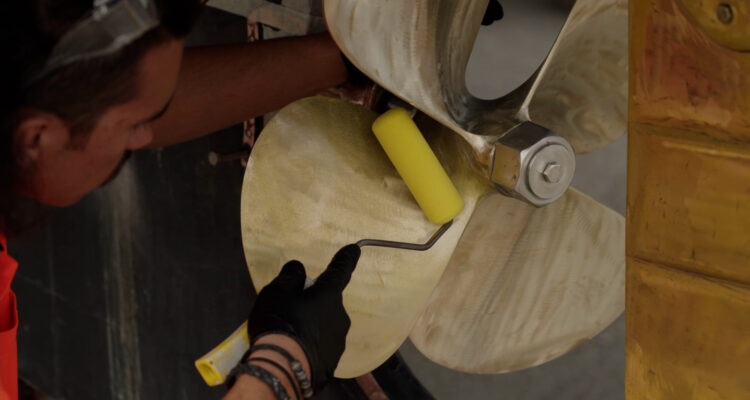 Applicator applying PropOne Primer to a boat propeller using a roller